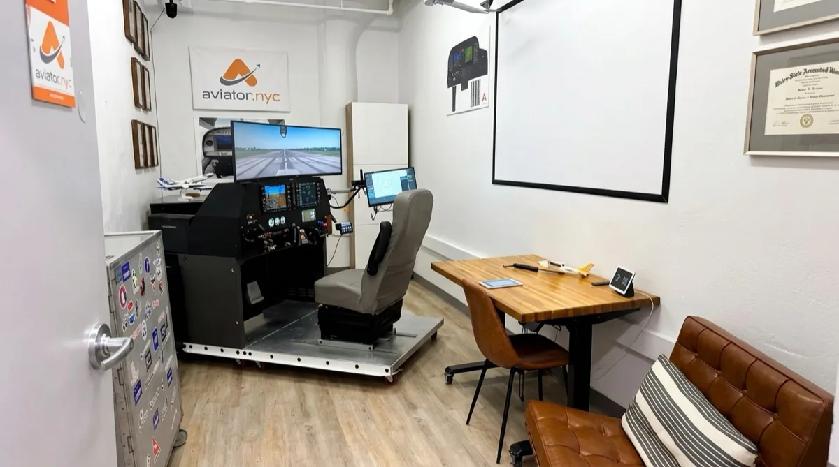 Aviator.NYC training facility with PFC GTX flight simulator, briefing table, and Embry-Riddle diploma — professional flight training in Manhattan