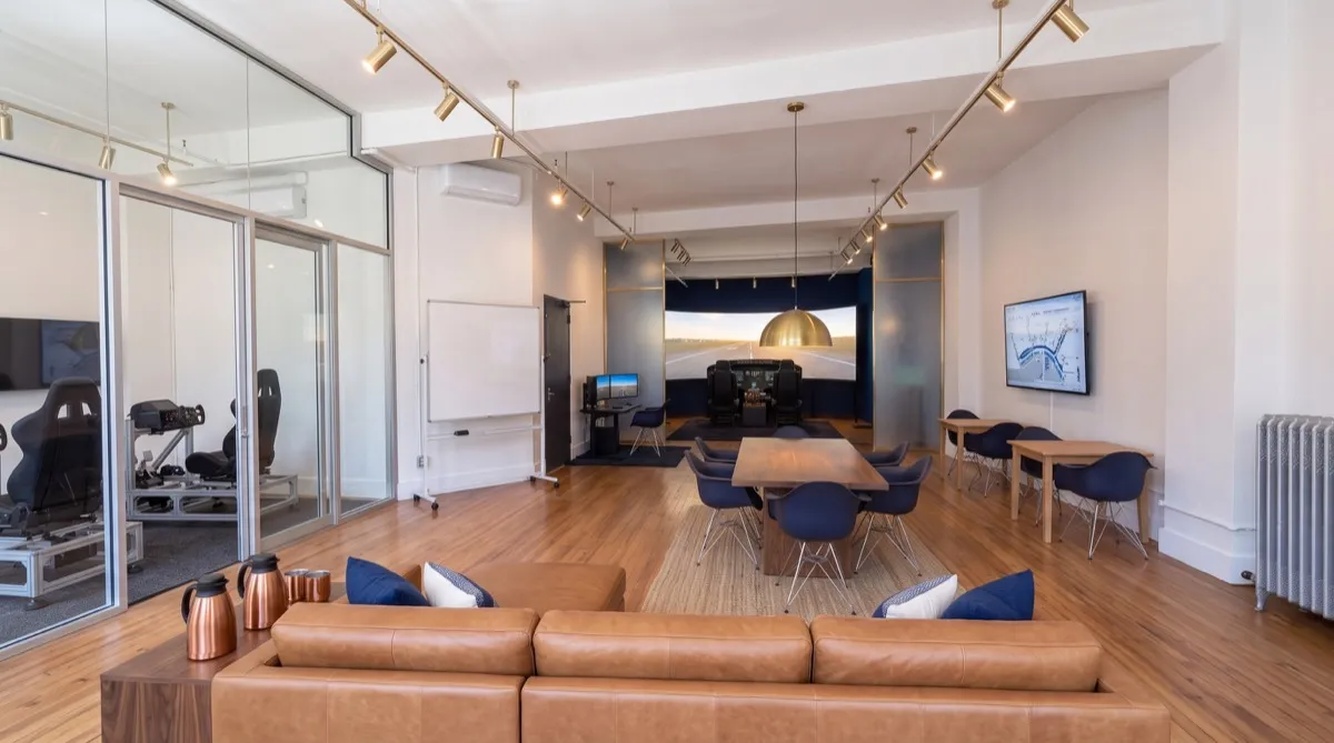 AI-generated rendering of the Cirrus G3000 simulator bay with a three-screen display at the back of the Aviator.NYC studio, seen past the briefing area
