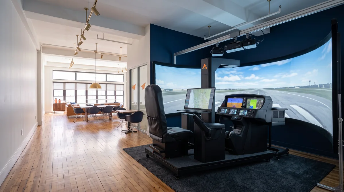 AI-generated rendering of the Cirrus SR-series simulator in the planned Midtown studio, with the conference and lounge area visible down the room beyond it